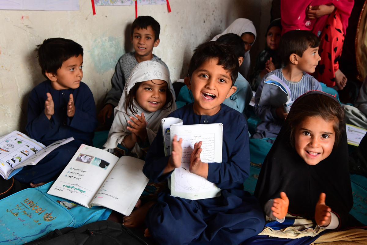 Children smiling in a packed classroom in Afghanistan