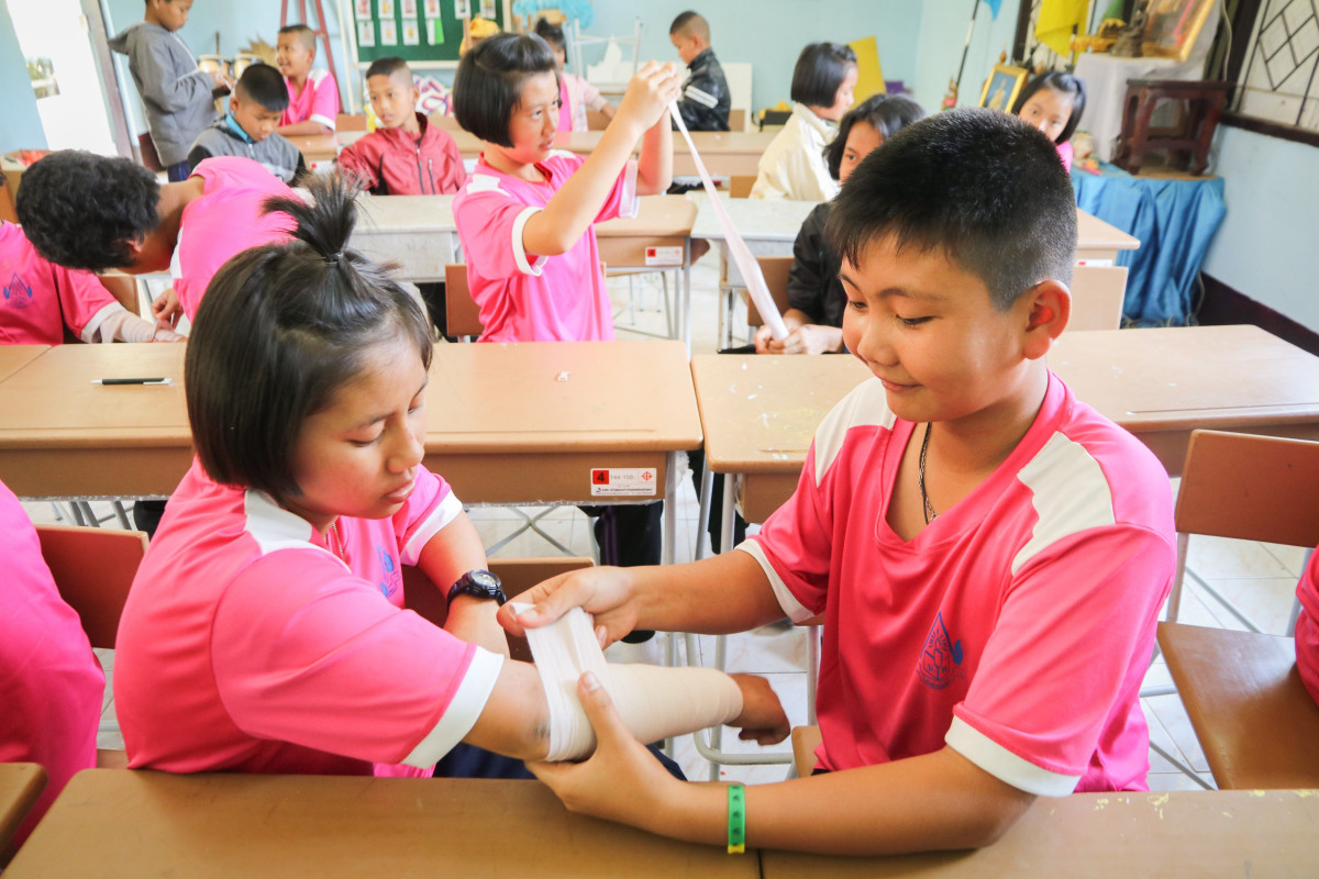 Two children practising first aid at school